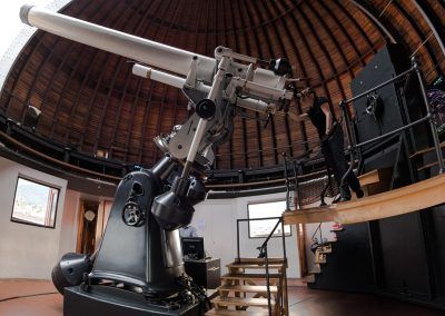 Demonstratorin blickt durch das Teleskop im Kuppelinneren